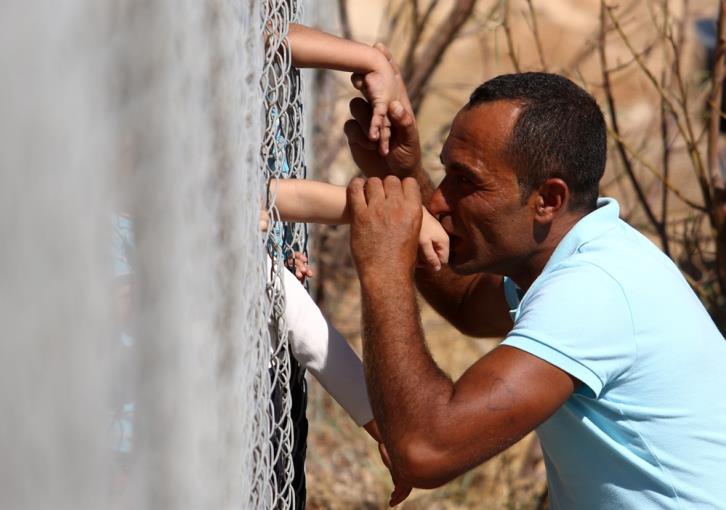 Συγκλονιστική εικόνα: Πρόσφυγας φιλάει τα χέρια των παιδιών του από την άλλη πλευρά του φράχτη (pics) 